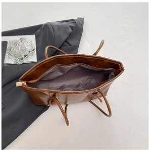 Détail du grand cabas en cuir marron avec fermeture éclair dorée et poignées nouées
