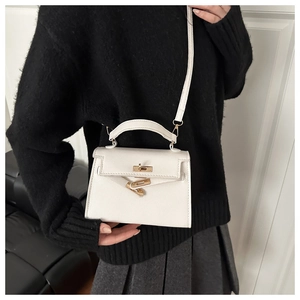 Detail of white lychee leather handbag featuring golden metal twist lock and top handle