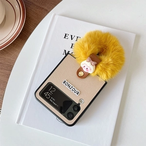 Detail of Galaxy Z Flip case featuring Bonjour lettering, brown leather strap and plush charm