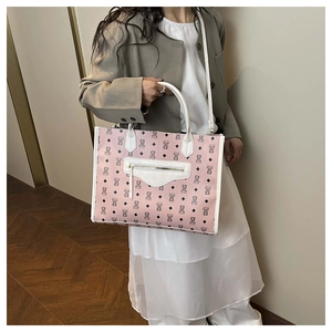 Detailed view of pink tote bag with bear monogram pattern on a model's shoulder