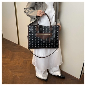 Detail of large black tote bag with white bear print and brown leather handles