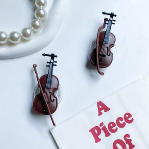 Detailed close-up of brown resin violin-shaped phone grips on artistic paper
