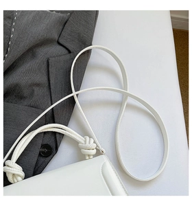 Dettaglio del manico annodato e della texture in pelle premium della borsa bianca