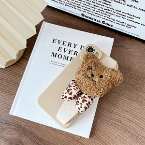 Detailed close-up of iPhone case featuring a plush teddy bear and leopard print wristband