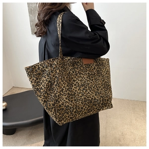 Close-up of leopard print canvas tote bag featuring a leather patch and exterior pocket