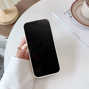 White iPhone case with wrist strap and bear detail held in a cozy lifestyle setting