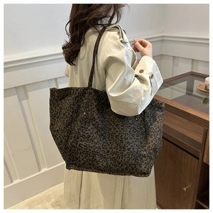 Detail of leopard print canvas tote bag with front pocket shown on a model