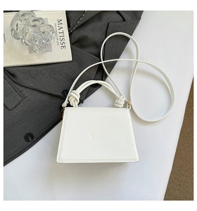 Borsa a mano bianca minimalista con manico a nodo presentata su un libro elegante