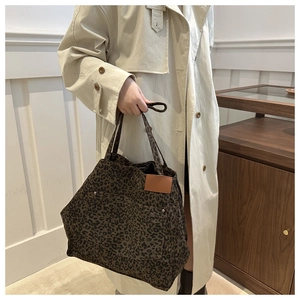 Detail of leopard print tote bag with front pocket, silver rivets and leather patch