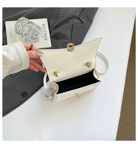 Dettaglio di una borsa in pelle bianca con fibbia dorata e scomparto interno