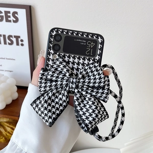 Detail of black and white houndstooth phone case with large bow and detachable strap