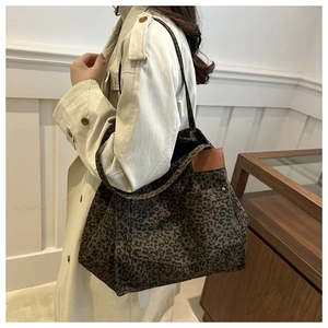 Detail of leopard print canvas tote bag with brown leather patches and metal rivets