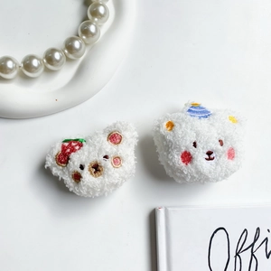Detail view of two cute plush bear air cushion phone grips with strawberry and hat embroidery