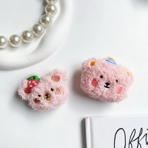 Detail of pink plush bear cases with strawberry and party hat embroidery on soft fabric