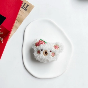Close-up of white plush bear phone grip with detailed red strawberry embroidery