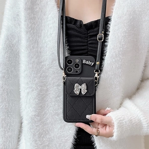 Detail of black leather phone case with quilted card slot, silver bow and crossbody strap