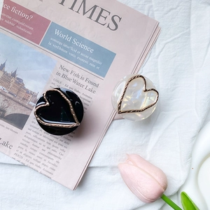 Detail of black and iridescent white marble phone grips with gold hollow heart accents