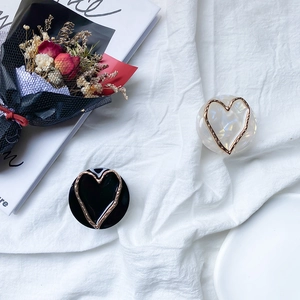 Detailed view of heart-shaped marble pattern phone grips in black and white finish