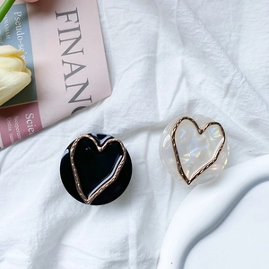 Marble texture heart phone grip stand with gold metallic trim on white fabric background