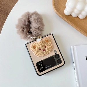Detail of cute bear embroidery and fuzzy pompom charm on Samsung Z Flip folding case