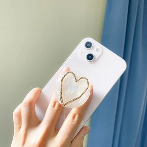 Elegant heart phone grip with marble texture and gold plating on a pink smartphone