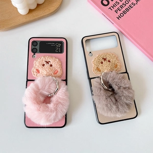 Detail view of pink and beige plush bear phone cases with fluffy faux fur ring handles