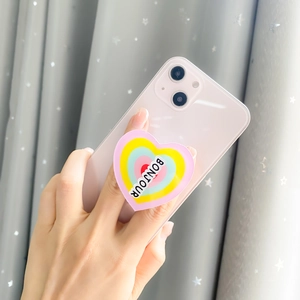 Rainbow heart-shaped phone grip with BONJOUR text shown on a pink smartphone