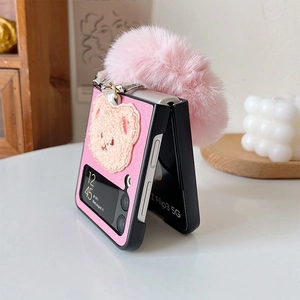 Detailed view of pink leather Z Flip3 case with plush bear charm and faux fur ball accessory