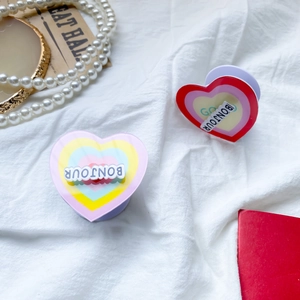 Detail of two colorful heart-shaped phone sockets with Bonjour text on white fabric