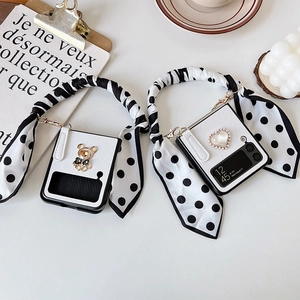 Detail view of Galaxy Z Flip phone case with stylish ribbon hand strap and bear charm