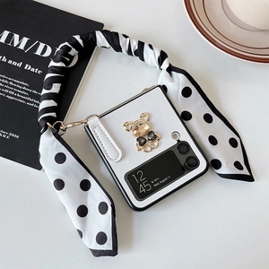 Detail of Samsung Z Flip case featuring a bear charm and polka dot silk ribbon handle