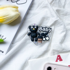 Detail of heart-shaped phone grip with black bear, baby letters and coffee cup decor