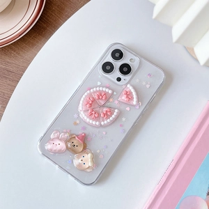 Vue macro d'une coque iPhone transparente avec ours 3D, paillettes et charmes gâteau