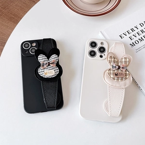 Close-up of phone case with decorative rabbit ear wrist strap and bow on desk