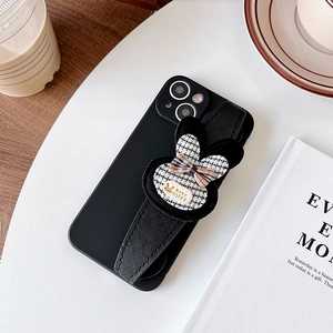 Detail of black phone case with tweed bunny hand strap on a desk with a coffee cup
