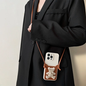 Crossbody iPhone case detail featuring a brown leather back and 3D plaid bear ornament