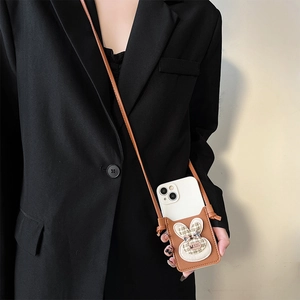 Brown leather crossbody phone case featuring a fabric rabbit motif and slim shoulder strap