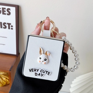 Detail of white lychee leather Z Flip 6 case with pearl strap and cute rabbit badge