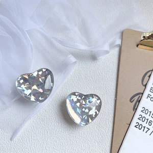 Detail of two heart-shaped laser rainbow acrylic phone grips on white textured background