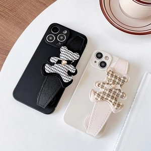 Protective iPhone cases with wrist straps featuring plaid bear charms in black and white