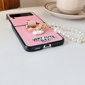 Pink leather Galaxy Z Flip 6 case with pearl wrist strap and rhinestone ring detail
