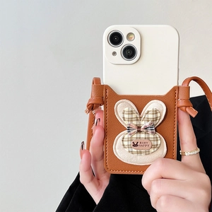 Detail of brown litchi leather phone wallet with plaid rabbit ears and crossbody strap