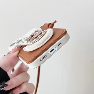 Detail view of iPhone case with brown leather card slot, bow, and adjustable strap