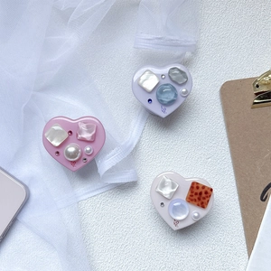 Set of heart-shaped phone socket grips with pearls and gemstones on lace background