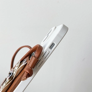 Macro detail of brown leather iPhone case featuring side strap and fine fabric stitching