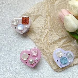 Detailed view of heart-shaped phone grips with resin stones, pearls and rhinestones