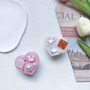 Macro detail of heart-shaped pop sockets with pearls and leopard patterns on a white background