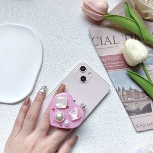 Pink heart-shaped Griptok with inlaid mother-of-pearl and pearls on a smartphone