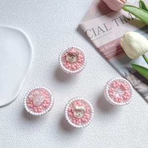 Close-up of pink 3D cake phone grips with cute resin bear, rabbit, and bow details