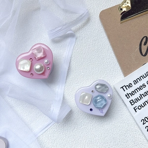 Detailed view of heart-shaped phone grips with pearls, rhinestones and 'LOVE' text